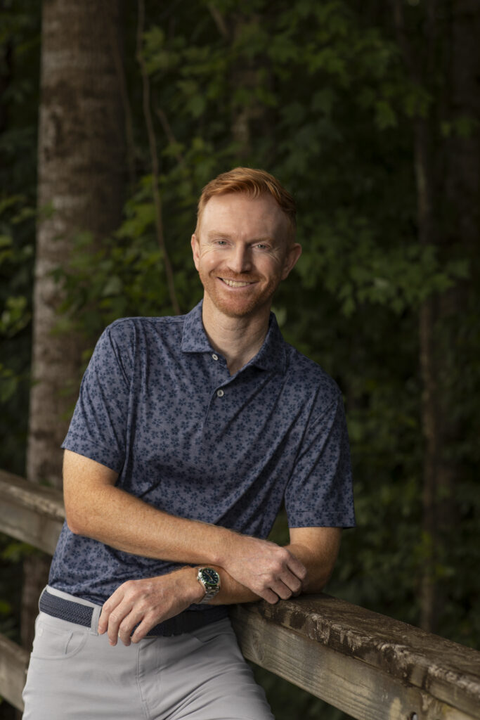 Kind man nonchalantly leans against a Independence Golf Club walking bridge for a professional outdoor headshot